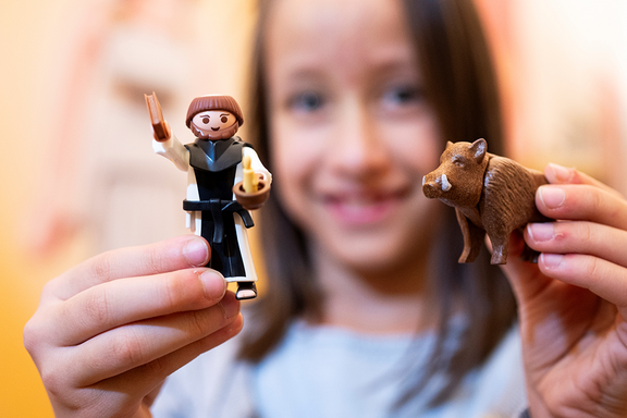 Ein Mädchen hält eine Mönch-Playmobil Figur in der Hand