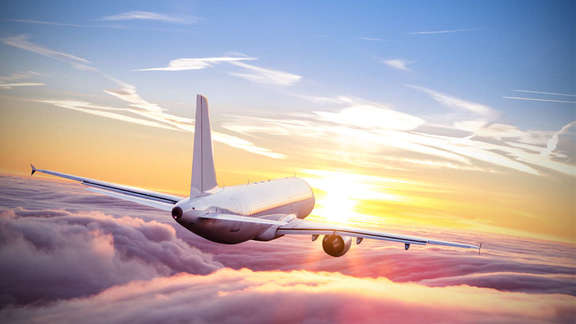 Vergrößerte Ansicht: Ein Flugzeug über den Wolken bei Sonnenuntergang