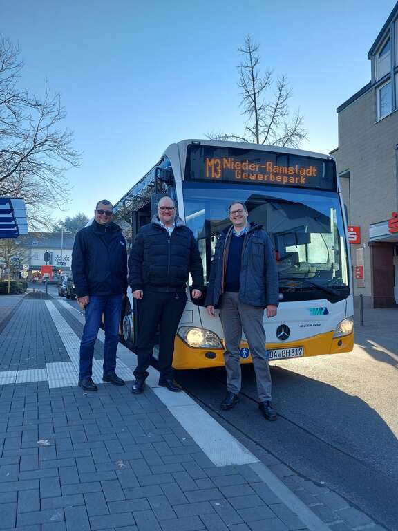 Drei Männer stehen vor einem Bus.