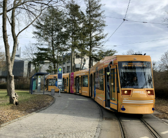 Gelbe Straßenbahn an einer Haltestelle im Grünen
