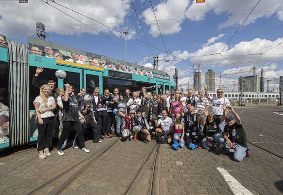 Pokalsieger-Straßenbahn Personengruppe mit Eintracht-Fan-Bekleidung jubelnd vor einer Eintracht Straßenbahn