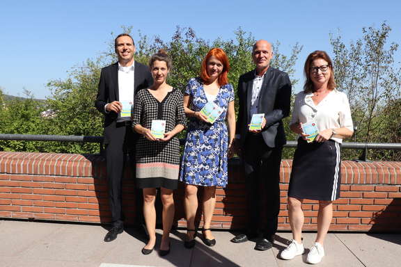 Beteiligte der Pressekonferenz halten das Klimasparbuch des Main-Taunus-Kreises in der Hand. MTV beteiligt sich am Klimasparbuch des Main-Taunus-Kreises.