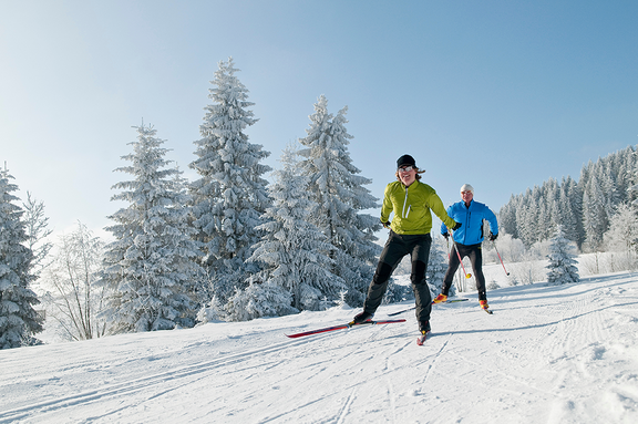 Eine Frau und ein Mann fahren bei blauem Himmel und Sonnenschein Ski 