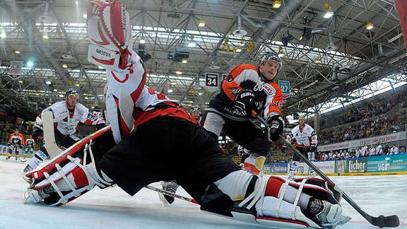 View from the goal: Ice hockey player runs towards the goalkeeper with his legs straddled