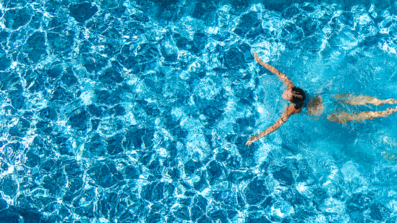 Eine Frau im hellblauen Bikini schwimmt im Wasser