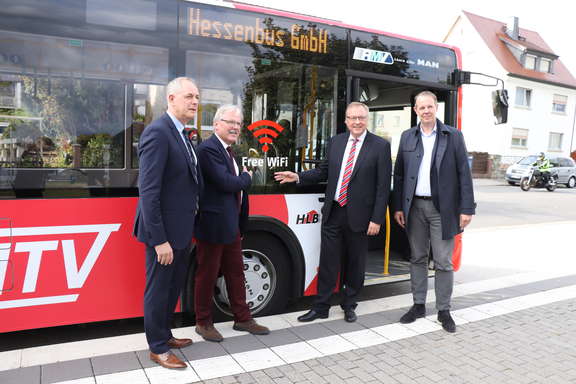 Beteiligte vor einem MTV-Bus mit WLAN-Hinweis. WLAN in Bussen im MTK.