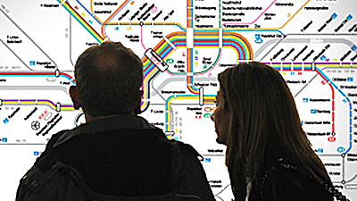 Paar steht vor einem Liniennetzplan und schaut ihn sich an