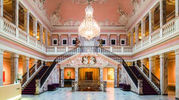 Der Marmorsaal mit Kronleuchter, doppeltem Treppenaufgang und Empore mit Säulengängen.