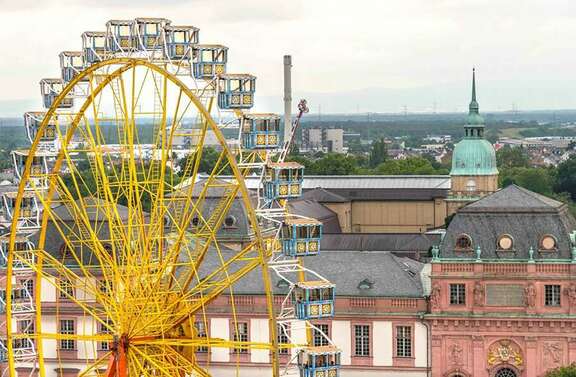 Ein großes gelbes Riesenrad vor dem Hintergrund historischer Gebäude in Darmstadt