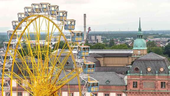 Ein großes gelbes Riesenrad vor dem Hintergrund historischer Gebäude in Darmstadt