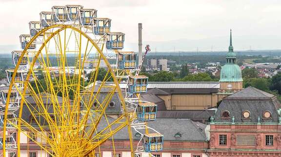 Ein großes gelbes Riesenrad vor dem Hintergrund historischer Gebäude in Darmstadt