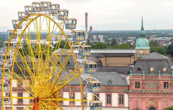Ein großes gelbes Riesenrad vor dem Hintergrund historischer Gebäude in Darmstadt