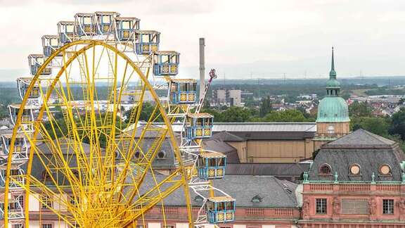 Ein großes gelbes Riesenrad vor dem Hintergrund historischer Gebäude in Darmstadt