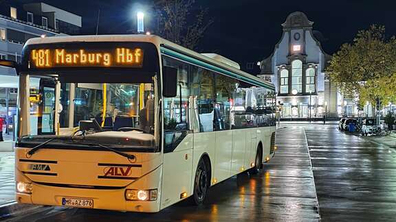 Bus mit Zielanzeige Marburg Hauptbahnhof steht nachts an Haltestelle