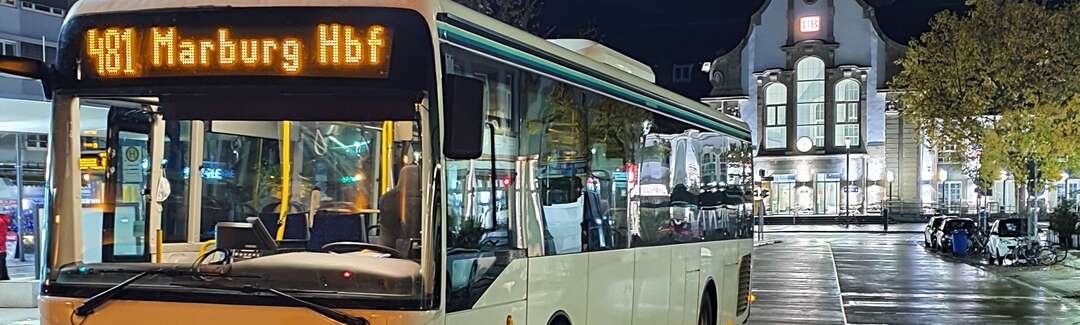 Bus mit Zielanzeige Marburg Hauptbahnhof steht nachts an Haltestelle