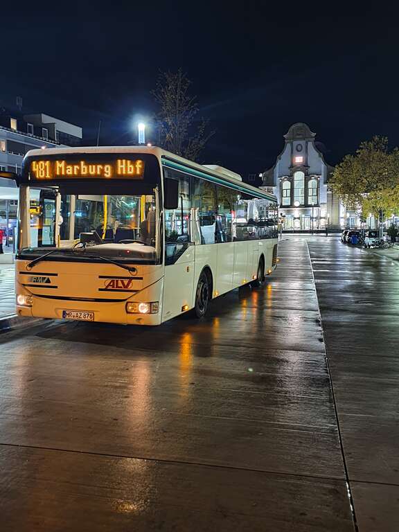 Bus mit Zielanzeige Marburg Hauptbahnhof steht nachts an Haltestelle