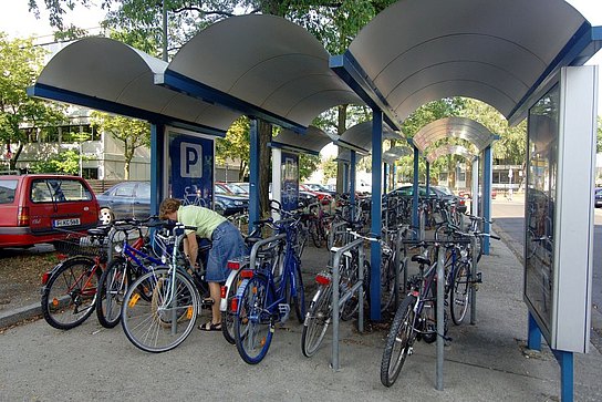 Frau schließt Fahrrad an Fahrradständer an