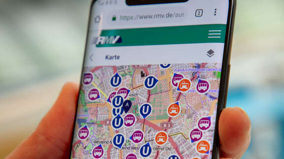Hand holding a mobile phone showing a Screenshot of the live map of the WebApp