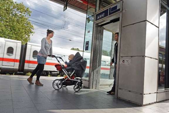 Woman with a pram getting on a lift on the platform