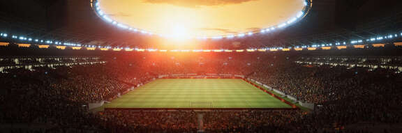 Vollbesetztes Fußballstadion mit Sonnenuntergang