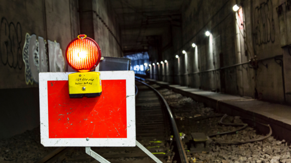 Blick in einen Tunnel. Links befindet sich ein Warnschild mit einer leuchtenden Baustellenlampe.