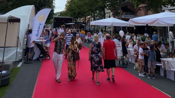 Besucher flanieren auf dem roten Teppich auf dem Wiesbadener Taunusstraßenfest an den Ständen vorbei.