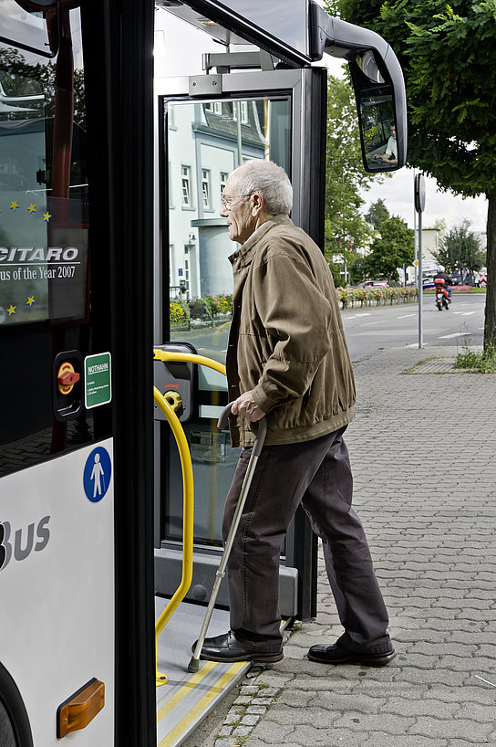 Barrierefreiheit Ein älterer Herr mit Gehstock steigt in einen Bus ein