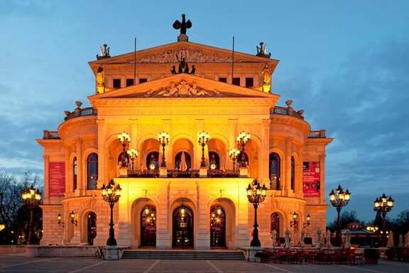 Klassizistisches Gebäude auf einem Platz, am Abend beleuchtet