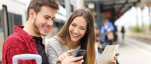 A young couple on the railway platform with a city map