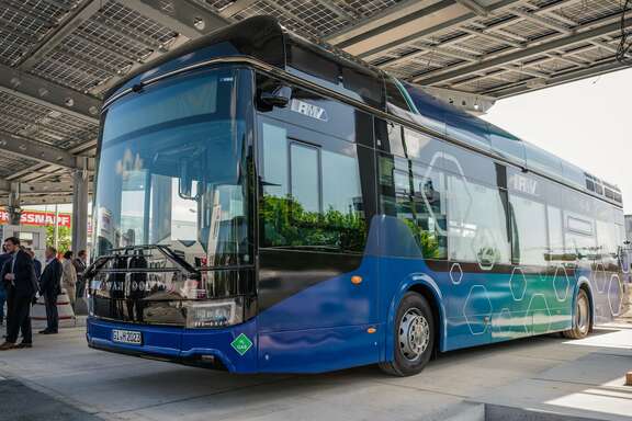 Blauer Van Hool-Bus unter einem Hallendach mit Solarpaneelen bei der Präsentation