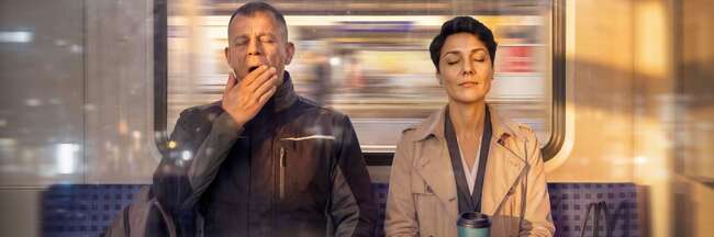 Eine Frau und ein Mann sitzen in einer Bahn, der Mann gähnt