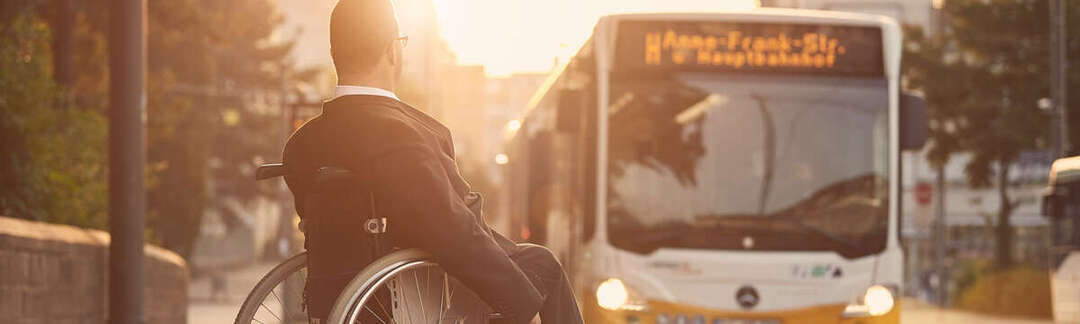 Rollstuhlfahrer blickt auf einen herannahenden Bus