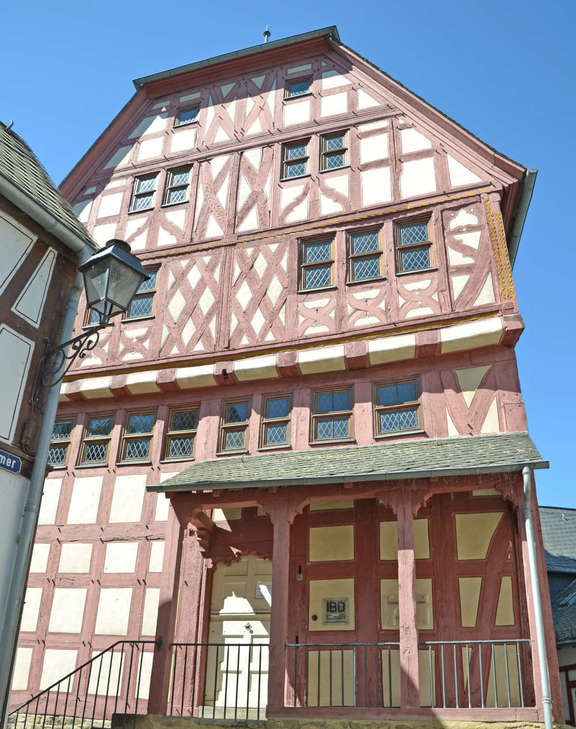 Römer 2-4-6 hohes Fachwerkhaus mit roten Balken und überdachtem Eingang