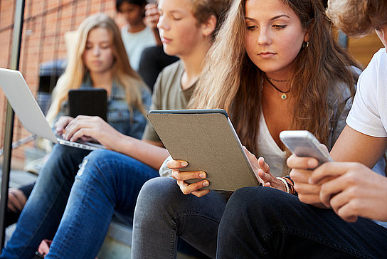 Schüler mit Laptop, Smartphone und Tablet