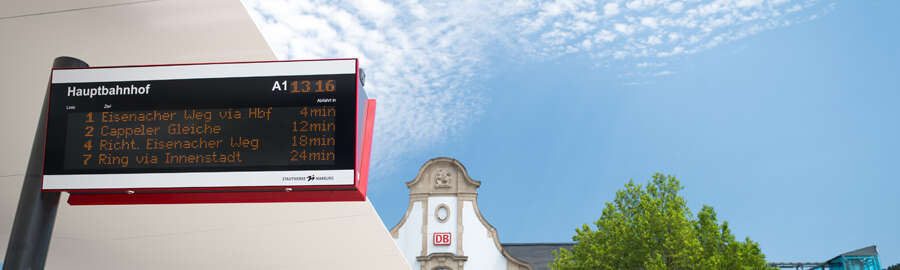 digitale Anzeigetafel am Bahnhofs-Vorplatz, im Hintergrund das Bahnhofs-Gebäude
