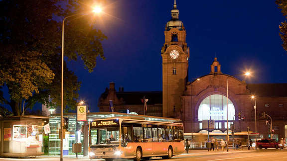 Vergrößerte Ansicht: Bus in der Dunkelheit an einer Haltestelle vor einem Bahnhofsgebäude