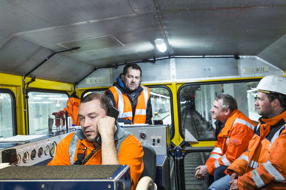 Im Bauzug Vier Arbeiter in einem Bauzug neben einer S-Bahn-Station
