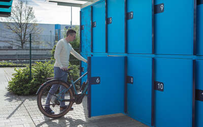 Ein Mann schiebt ein Fahrrad in die Fahrradbox.