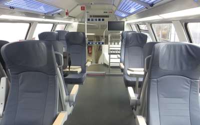 Vergrößerte Ansicht: graue Sitze im oberen Abteil eines Zuges durch einen Flur getrennt