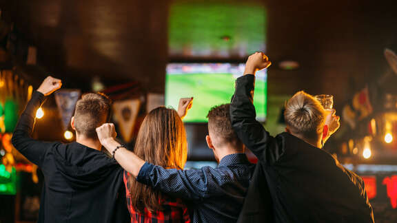 Public viewing Jubelnde Fans in einem Lokal vor einem Monitor
