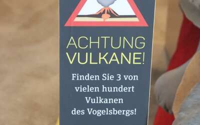 Warnschild mit Aufschrift: Achtung 3 Vulkane. Finden Sie 3 von 100 Vulkanen des Vogelbergs!