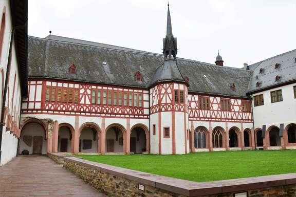 eine abgesetzte Rasenfläche umgeben von weißen historischen Gebäuden mit Sandsteinbogen