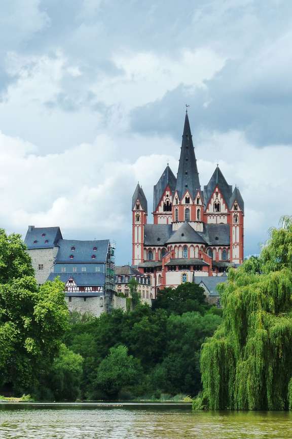 Von hier sehen Sie alle sieben Türme. Dom mit rot-weißer Fassade erhebt sich über Fluss mit Baum-bewachsenem Ufer