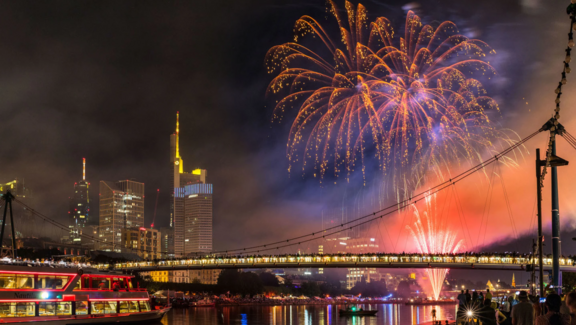 Feuerwerk vor der Frankfurter Skyline, Menschen stehen auf dem Holbeinsteg, ein Schiff ist auf dem Main unterwegs