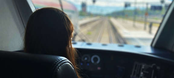 Eine Frau sitzt in der Führerstandskabine einer S-Bahn und schaut auf die Gleisen