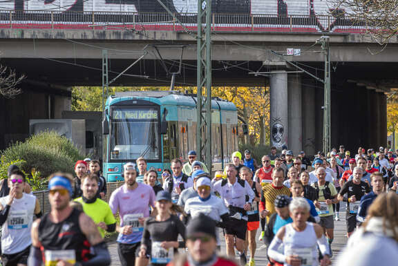 Marathonläufer im Vordergrund, hinten eine Straßenbahn