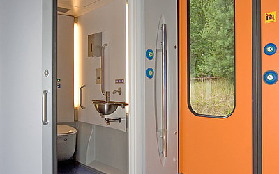 Vergrößerte Ansicht: Behindertenfreundliche Toilette neben orangener Eingangstür 