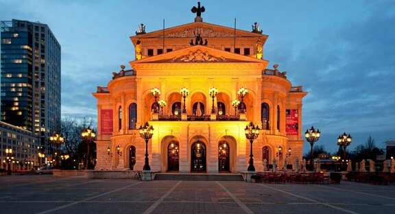 Klassizistisches Gebäude auf einem Platz, am Abend beleuchtet
