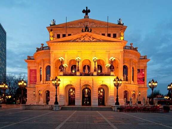 Klassizistisches Gebäude auf einem Platz, am Abend beleuchtet