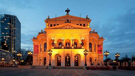 Klassizistisches Gebäude auf einem Platz, am Abend beleuchtet